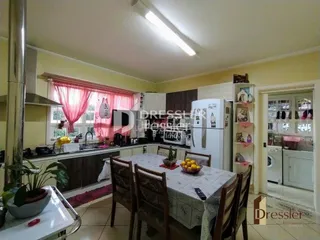 Uma sala de jantar com mesa de madeira e janelas em um imóvel no Brasil.