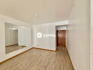 Hall de entrada com piso de madeira e espelho na parede.
