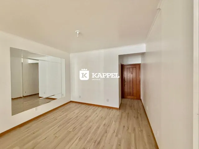 Hall de entrada com piso de madeira e espelho na parede.