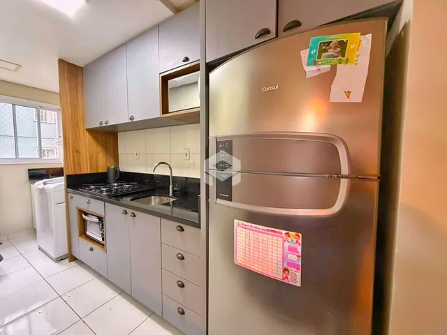 Foto de uma cozinha com armários brancos e bancada escura.