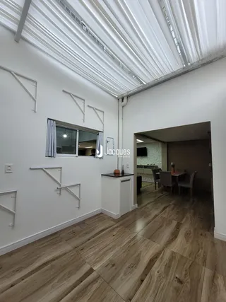 Ambiente interno de uma sala com piso de madeira e teto inclinado.