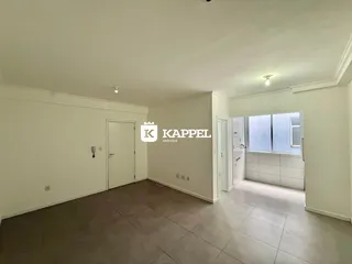 Foto de uma sala ampla e vazia com paredes brancas e piso de porcelanato.