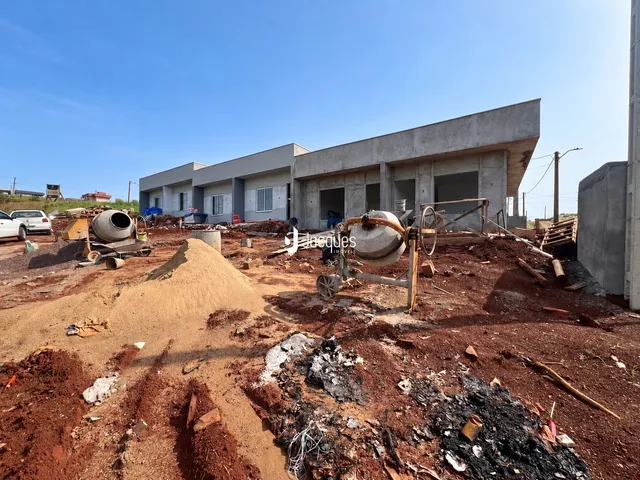 Vista externa de uma construção em terreno com terra exposta e maquinário antigo.