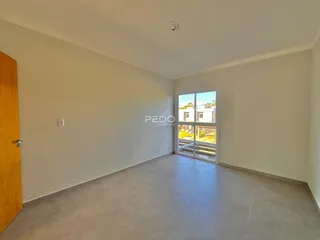 Interior de uma sala de estar com piso de cerâmica e porta de vidro abrindo para o exterior.