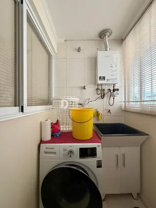 Foto de um ambiente interno mostrando uma máquina de lavar roupa e um balde amarelo.