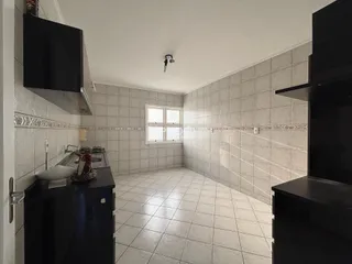 Imagem de uma cozinha com piso de cerâmica e paredes de azulejo claro.