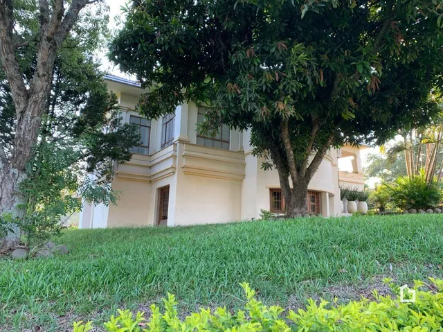 Fachada de uma residência em Lajeado, Brasil, vista através de vegetação.