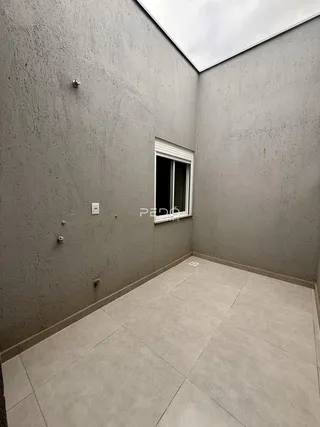 Vista de um corredor interno com paredes cinzas e piso de cerâmica.