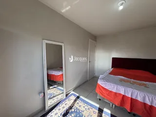 Quarto com cama e espelho refletindo o ambiente.