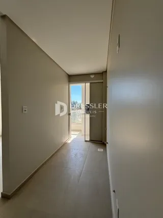 Corredor interno de uma residência com paredes brancas e piso claro.