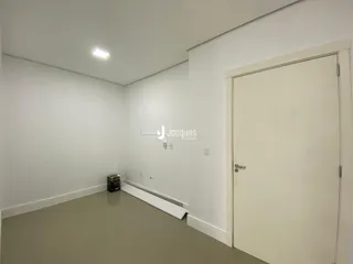 Interior de um cômodo vazio com paredes brancas e piso bege claro.