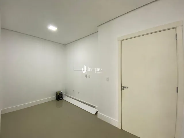 Interior de um cômodo vazio com paredes brancas e piso bege claro.