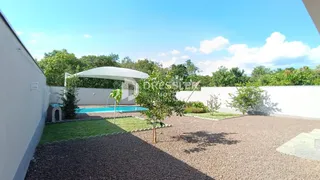 Vista externa de uma área de jardim com piscina e vegetação.