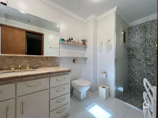 Banheiro moderno com revestimento de azulejos e bancada de mármore.