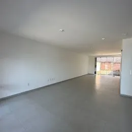 Vista interna de um corredor amplo com piso cinza e paredes brancas.