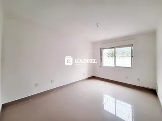 Foto de um ambiente interno vazio com paredes brancas e piso claro.