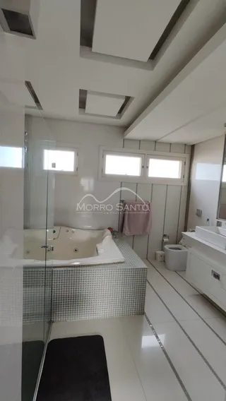 Foto de um banheiro com revestimento de azulejos e box de vidro.