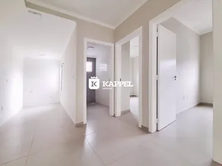 Foto do corredor interno de uma residência com paredes brancas e piso claro.