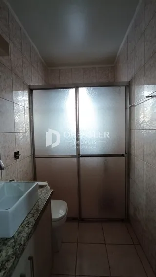 Foto de um banheiro com azulejos brancos e piso de cerâmica.