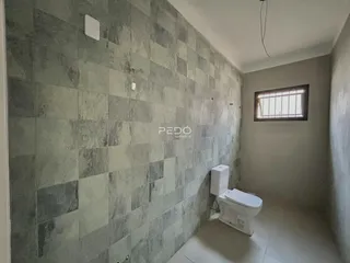 Foto de um banheiro com revestimento de azulejos cinzas e vaso sanitário branco.