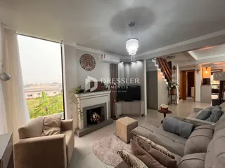 Sala de estar com lareira e grande janela de vista para a paisagem.