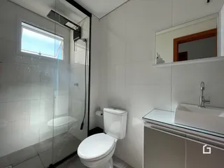 Foto de um banheiro com box de vidro e revestimento branco.
