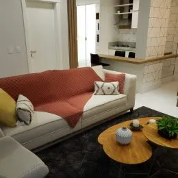 Uma sala de estar com um sofá branco e detalhes em tons de laranja.