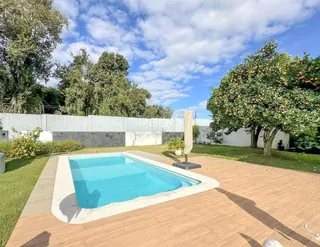 Foto da piscina e área externa com deck de madeira e jardim.