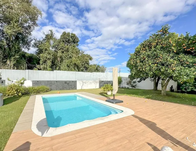 Foto da piscina e área externa com deck de madeira e jardim.