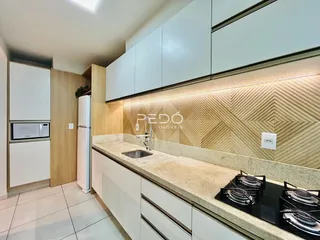 Cozinha moderna com armários brancos e bancada clara em um imóvel no Brasil.