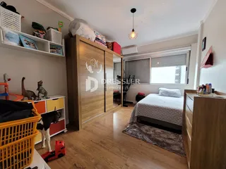 Quarto com armário de madeira e cama em um ambiente claro.