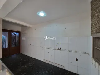 Hall de entrada com paredes brancas e piso escuro.
