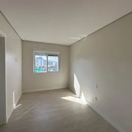 Ambiente interno com paredes brancas e piso de madeira clara.