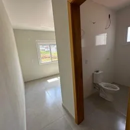 Hall de entrada com paredes brancas e piso claro.