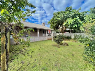 Foto da fachada de uma casa com jardim e vegetação.