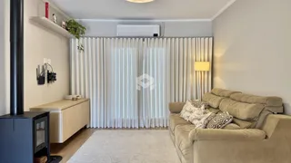 Sala de estar com sofá e cortinas brancas em um apartamento.
