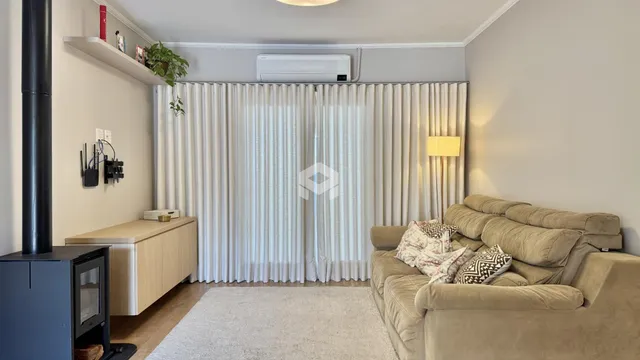 Sala de estar com sofá e cortinas brancas em um apartamento.