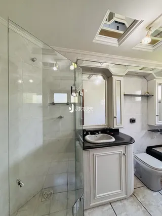 Foto de um banheiro com box de vidro e bancada.