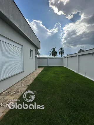 Fachada de uma residência branca com jardim gramado.