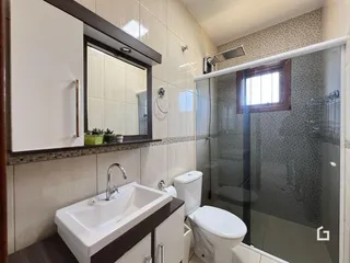 Foto de um banheiro com revestimento cerâmico e box de vidro.