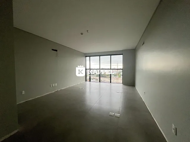 Foto de um ambiente interno amplo com piso claro e grandes janelas.