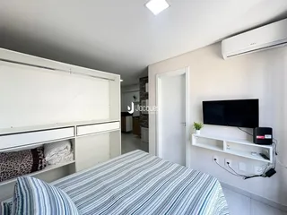 Quarto com cama e televisão montada na parede.