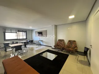 Ambiente interno de uma sala de jantar ampla com mesas e cadeiras.