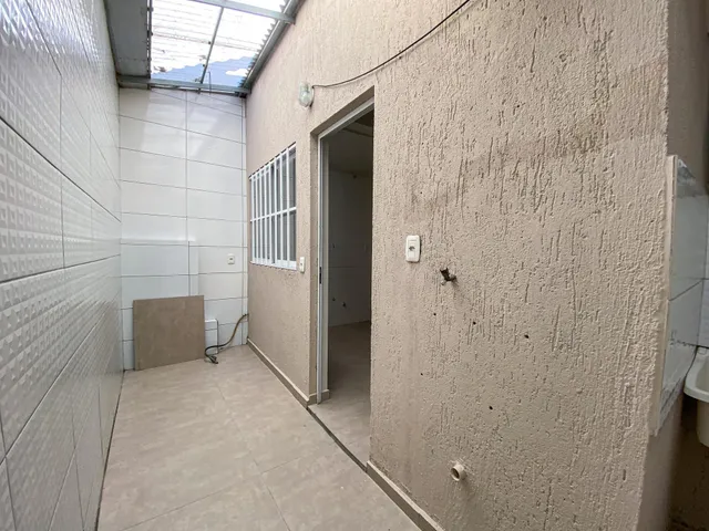 Um corredor interno com paredes texturizadas e piso de cerâmica.