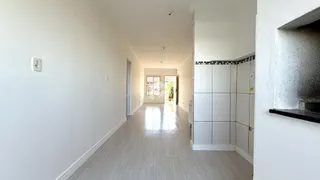 Corredor interno de uma residência com piso claro e paredes brancas.