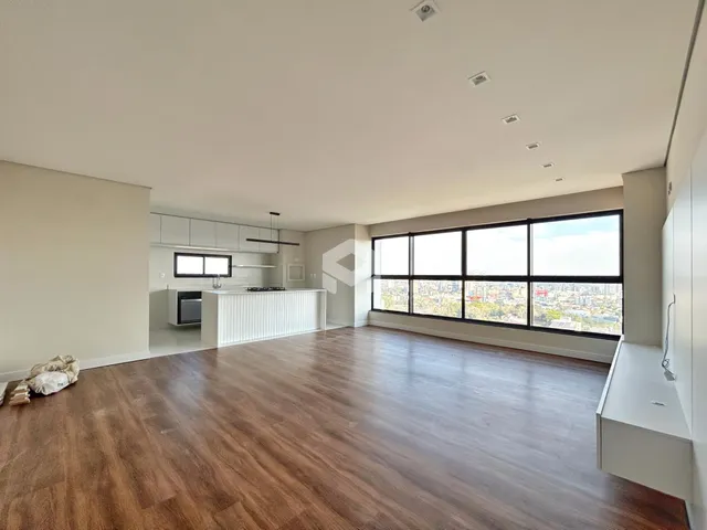 Sala de estar com piso de madeira e grandes janelas que oferecem vista da cidade.