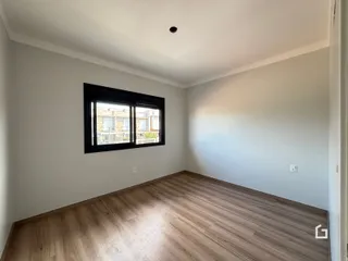 Sala de estar com piso de madeira clara e janela.