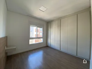 Ambiente interno de uma sala com piso de madeira clara e armários embutidos.