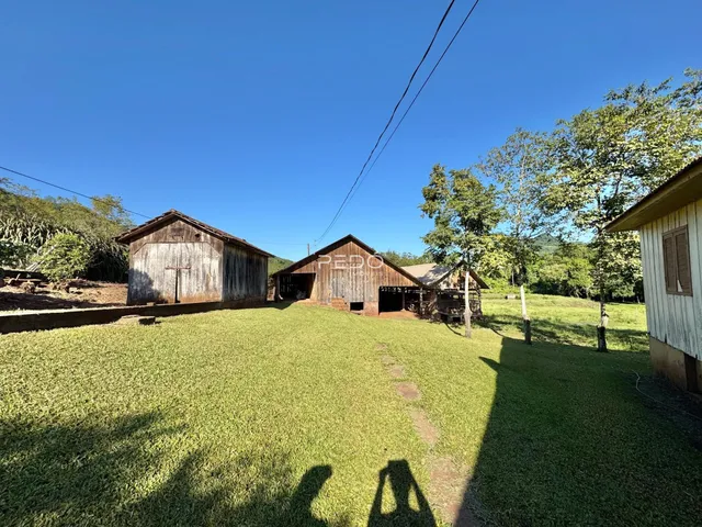 Vista externa de um campo gramado com estruturas de madeira no Brasil.