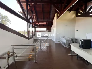 Vista interna de um ambiente com pé direito alto e estrutura de madeira aparente.